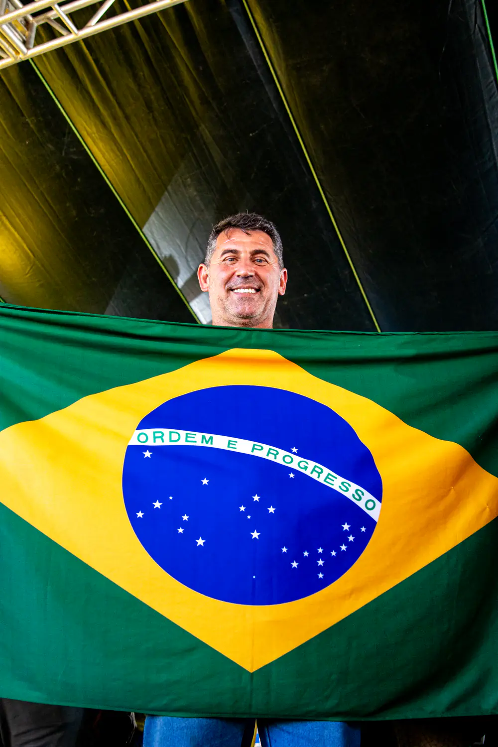 Sidnei Bonacolsi segurando a bandeira do Brasil aberta à sua frente.