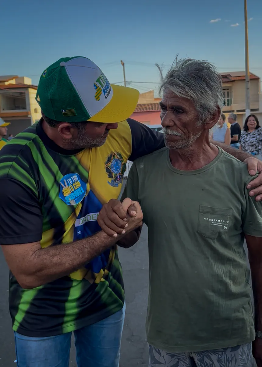 Sidnei Bonacolsi cumprimenta um senhor de camiseta verde durante caminhada em uma rua.